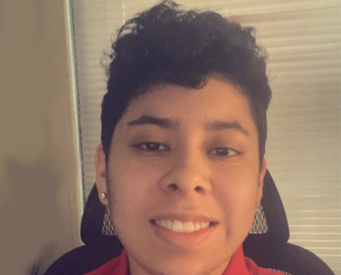 Photo of Alex Rodriquez sitting in a chair, that is in front of a window with closed blinds. Alex is wearing a red polo.